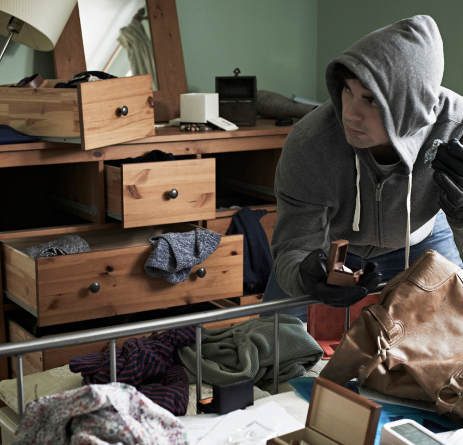 man burglarizing a room pulling drawers from a dresser